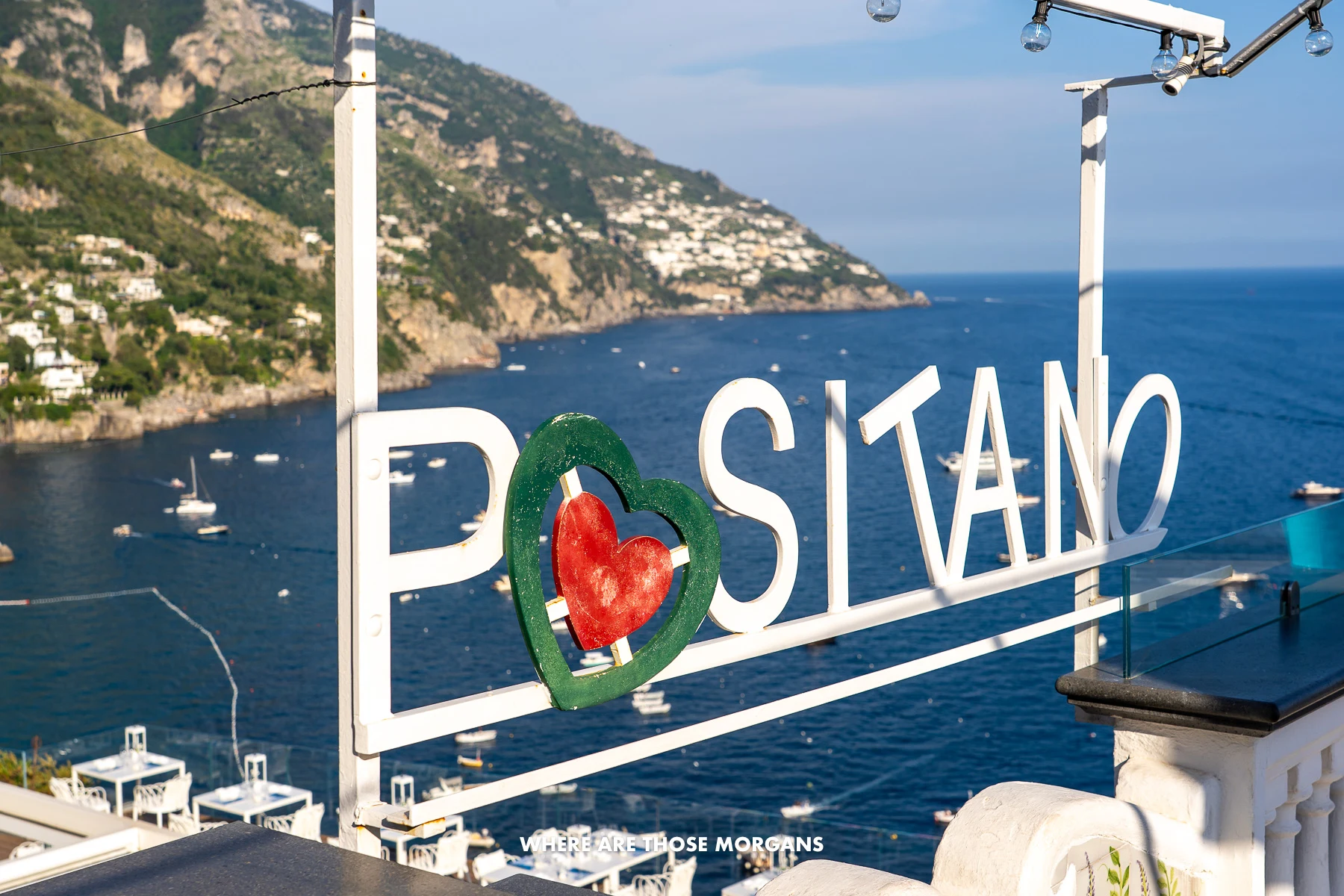 Photo of a white written Positano sign backed by the deep blue sea on the Amalfi Coast