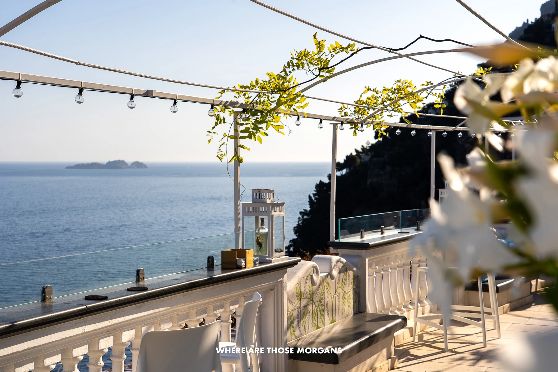 Photo of a white restaurant balcony with flowers overlooking the Tyrrhenian Sea on a sunny clear day