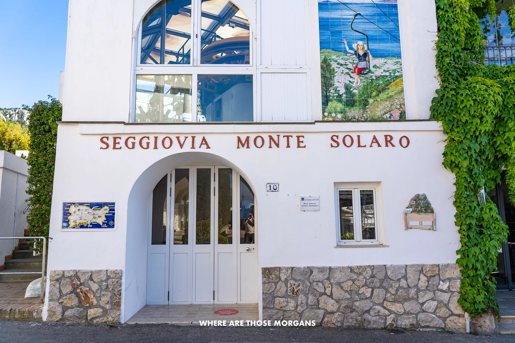 Photo of a white washed building with the words Seggiovia Monte Solaro in red letters and a tiled painting above