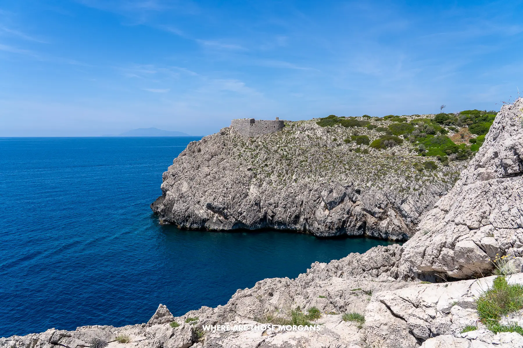 Photo of an old fort on a rocky coastline on a clear day in Italy