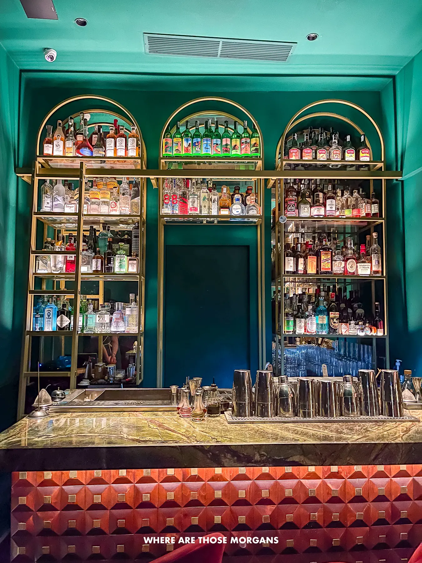 Photo of a speakeasy cocktail bar with a range of bottles on shelves behind a fancy looking bar
