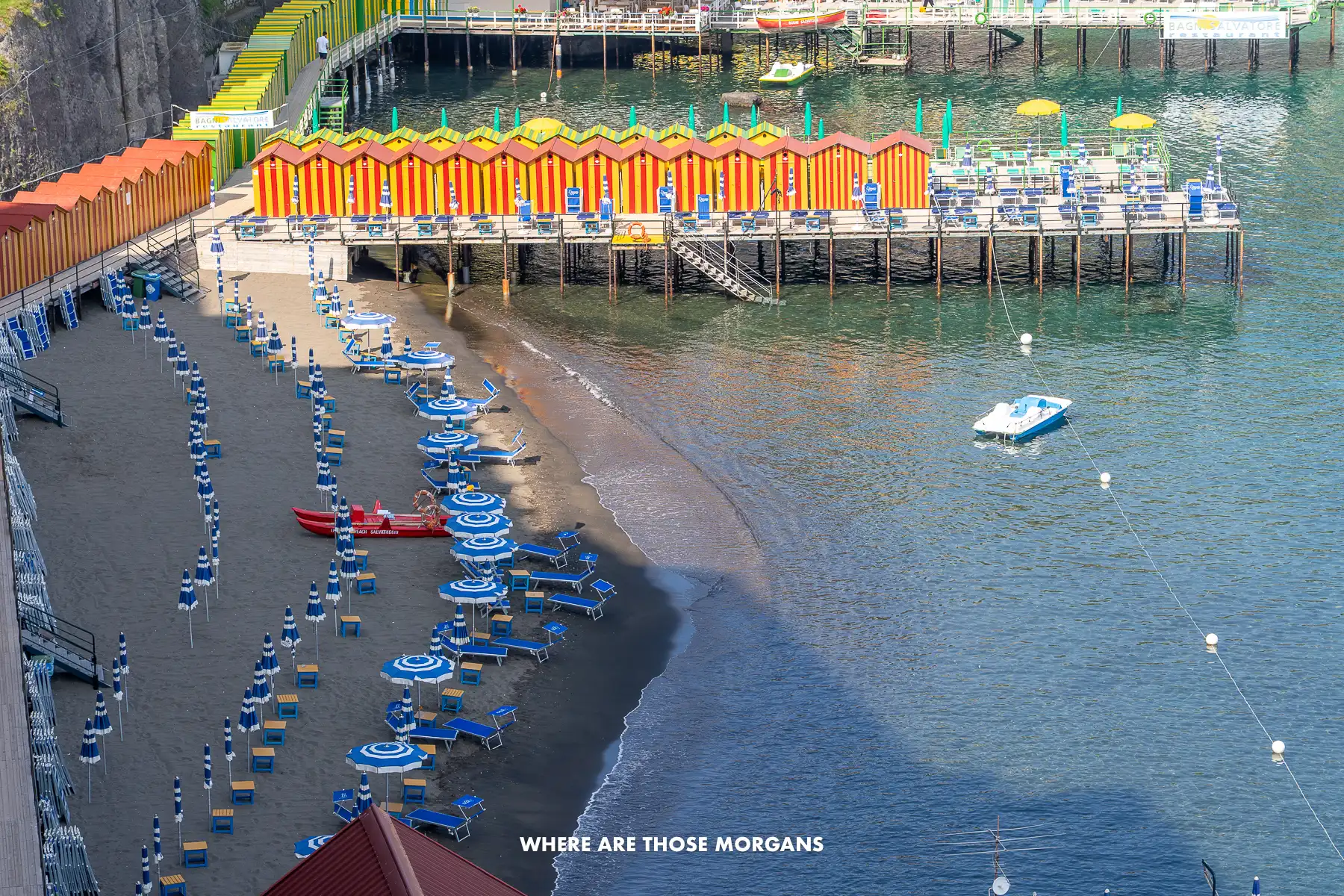 Photo of a small pebble beach with sun loungers and a wooden pier