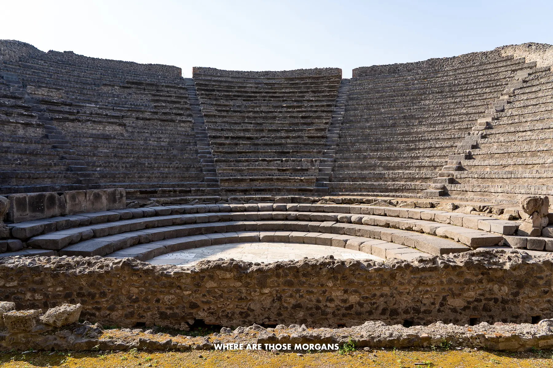 Photo of a small ruined theater with stone steps behind an old stage area