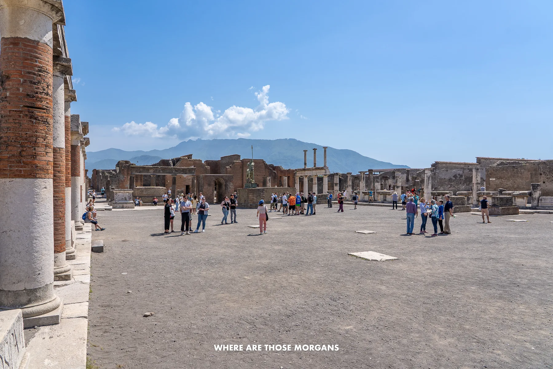 Photo of a wide open ruin in Italy on a sunny day with tourists exploring
