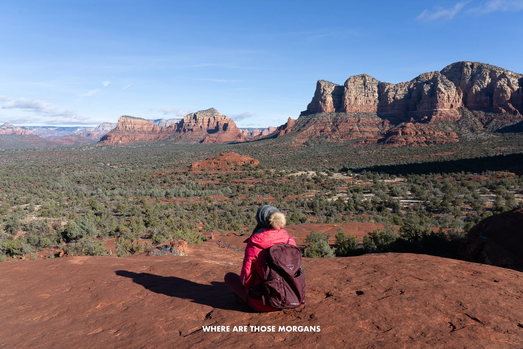 Photo of Kristen Morgan sat on red rocks overlooking a wide-open view of Sedona's red rocks and tree-filled valleys