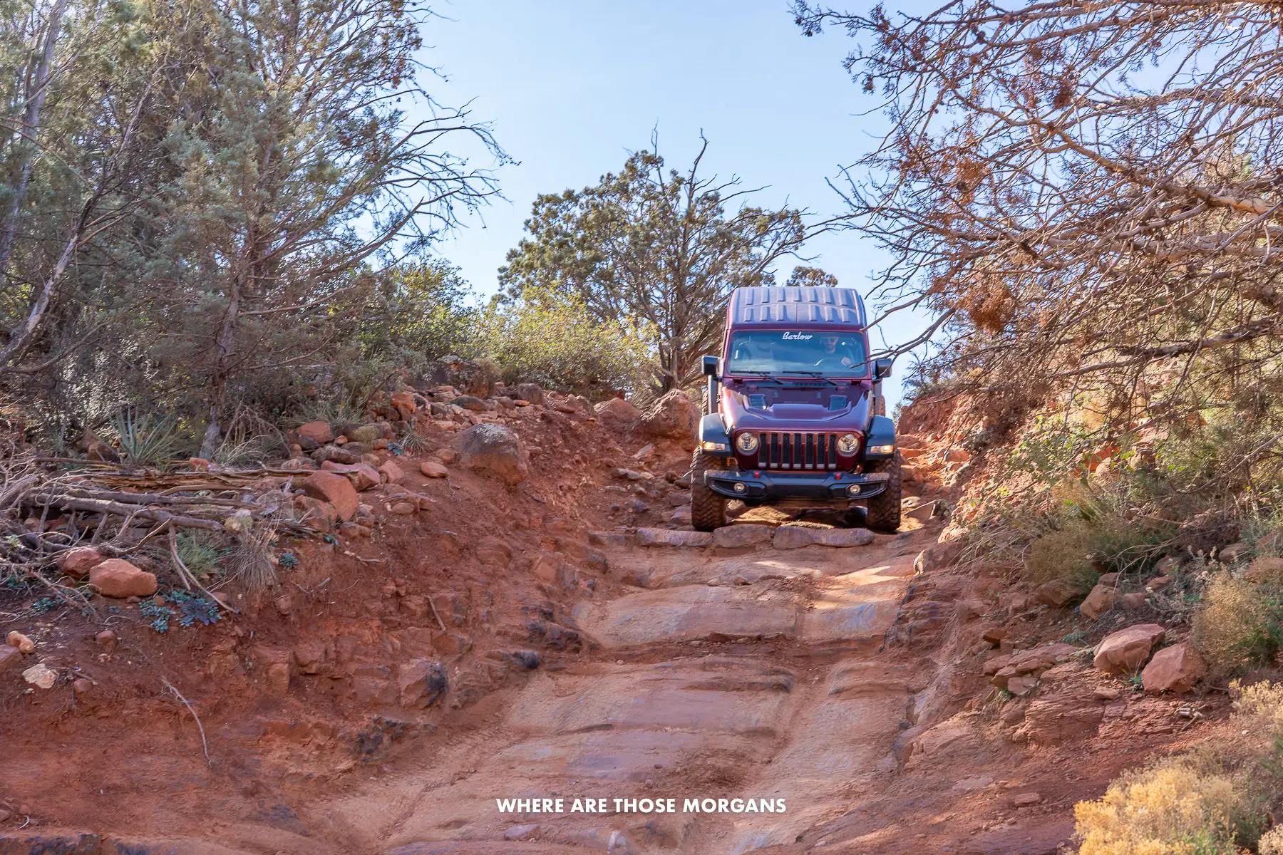 Photo of a maroon jeep driving down a steep red rock staircase in Arizona