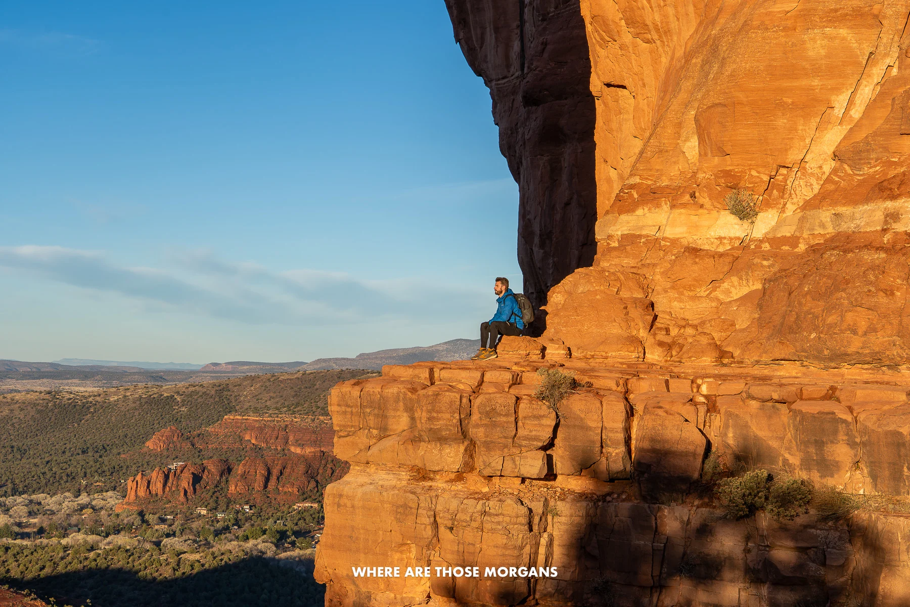 Photo of Mark Morgan sat on a rocky summit edge at the top of a hike in Sedona at sunrise