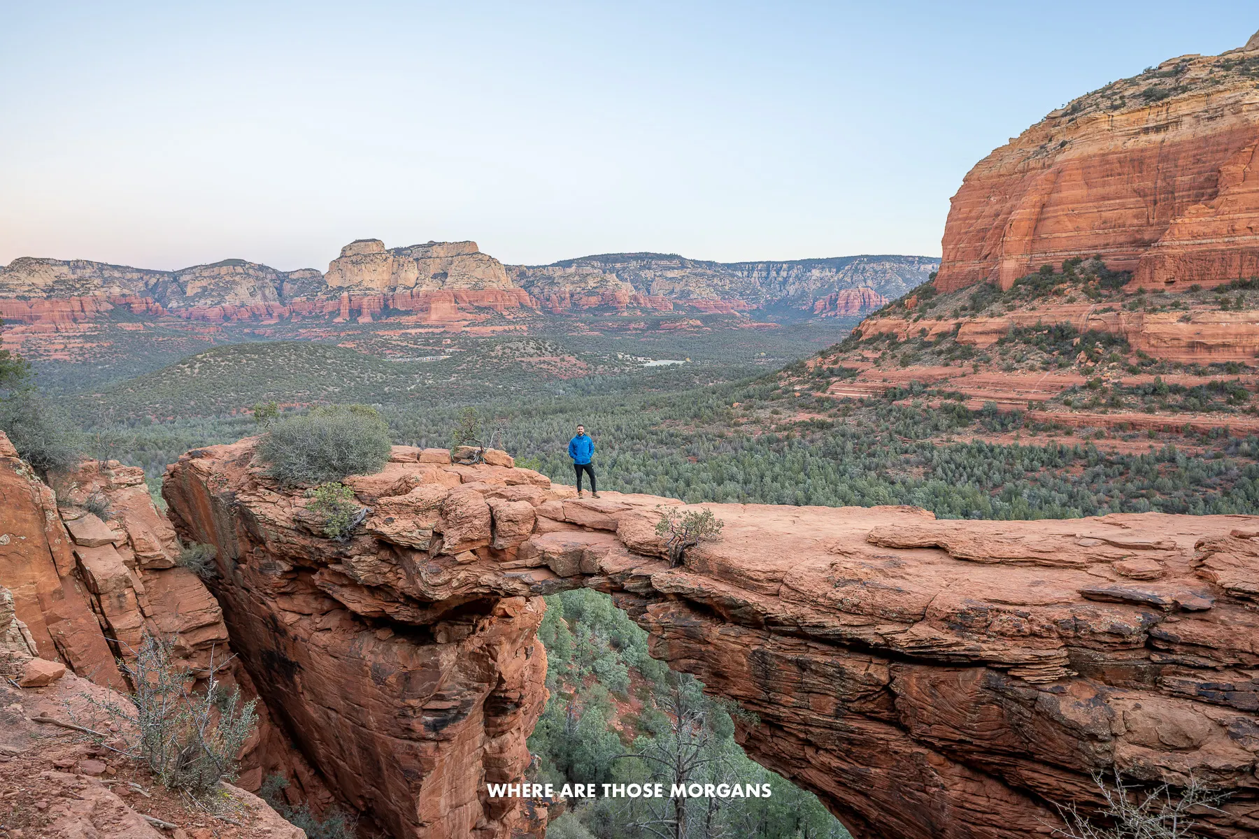 Photo of Mark Morgan standing alone on a sandstone formation called Devils Bridge in Sedona with open views behind
