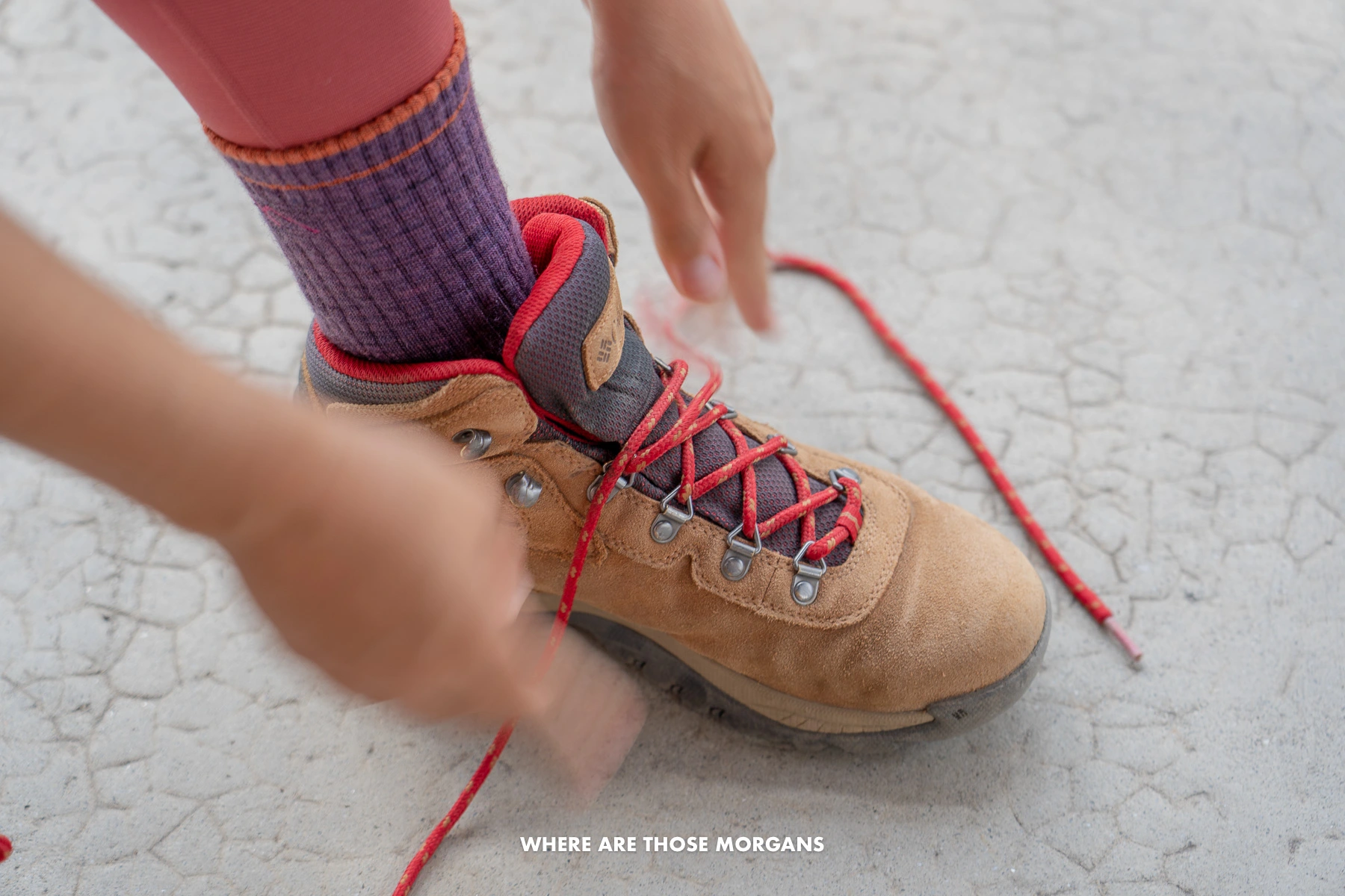 A woman tying her Columbia boot wearing Darn Tough Socks