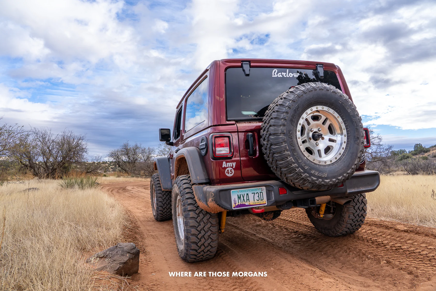 Photo of a maroon colored jeep on a dirt trail in Arizona