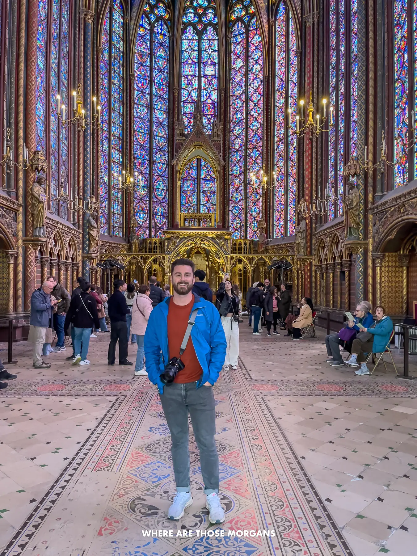 Photo of Mark Morgan standing with a camera inside Saint-Chapelle with other tourists enjoying the stained glass windows
