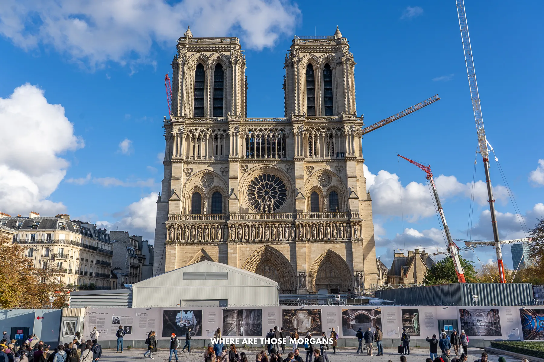 Photo of the outside of Notre-Dame de Paris with boards up and cranes working on rebuilding after the fire