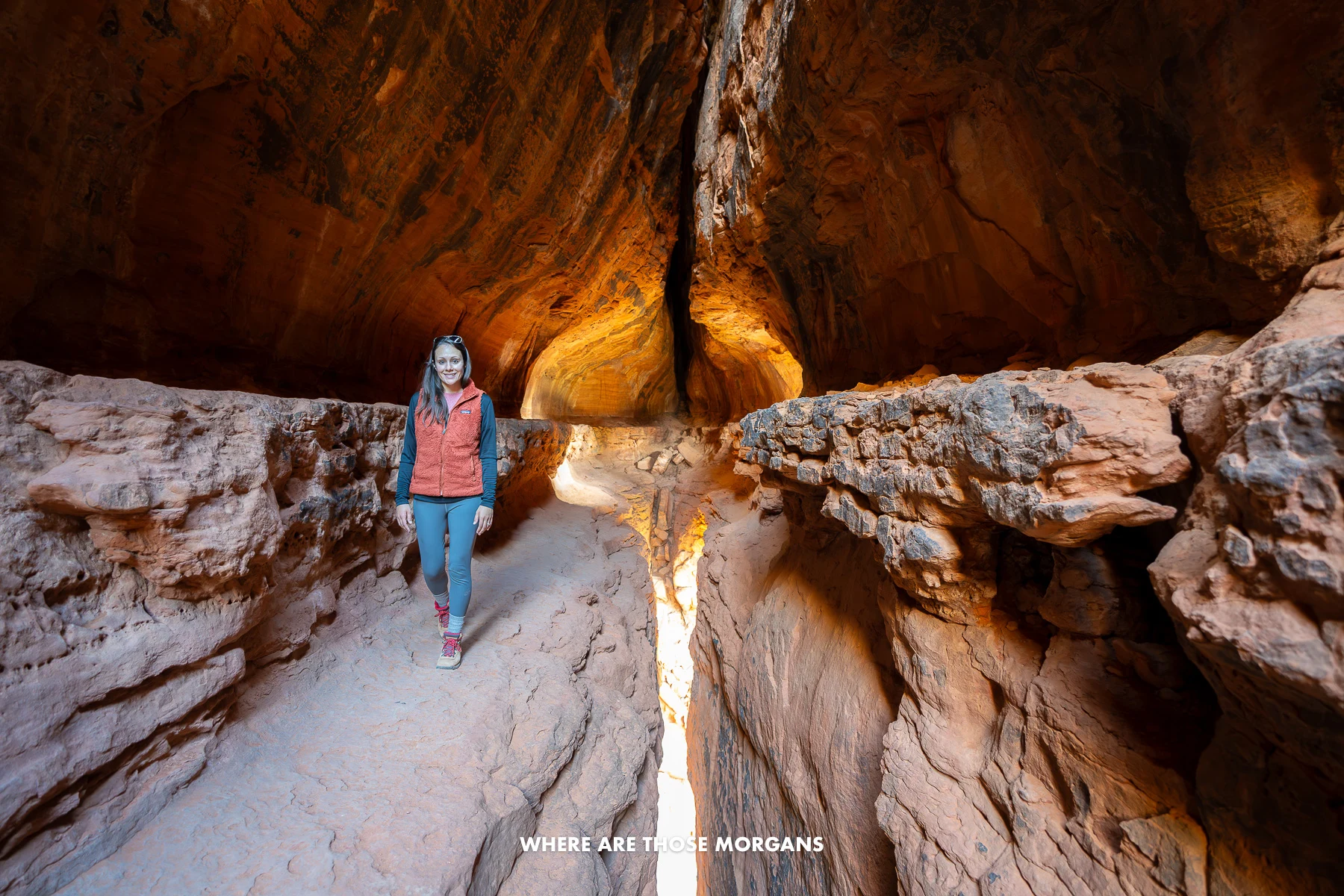 Photo of Kristen Morgan walking through a cave with light streaming in