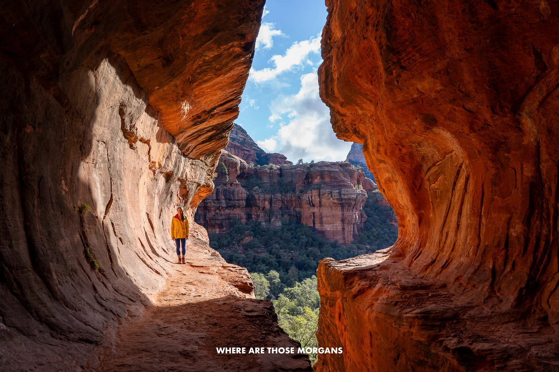 Photo of Kristen Morgan in yellow coat walking alone through a subway-tunnel shaped red rock formation