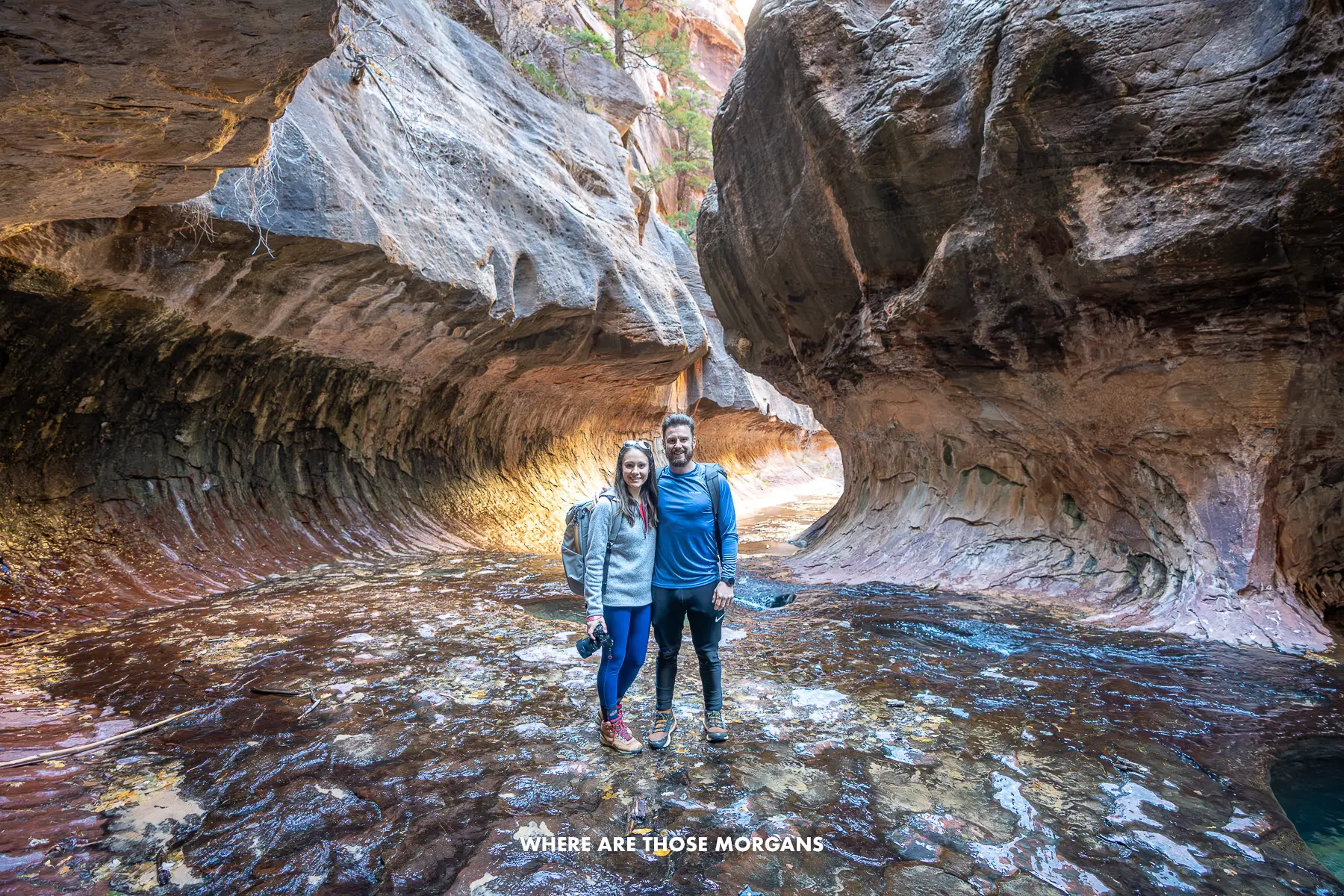 Photo of Mark and Kristen from Where Are Those Morgans standing together inside a natural subway tunnel shaped rock formation in Zion National Park