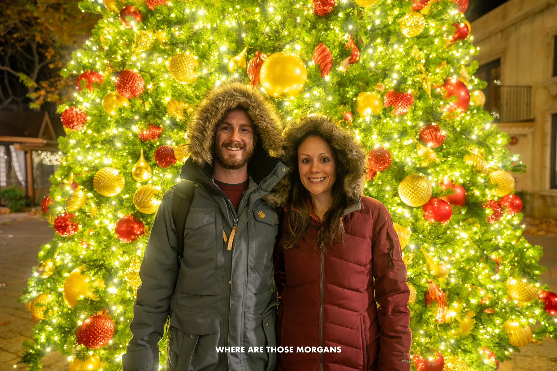 Photo of Mark and Kristen Morgan in winter coats in front of a Christmas Tree in Sedona AZ