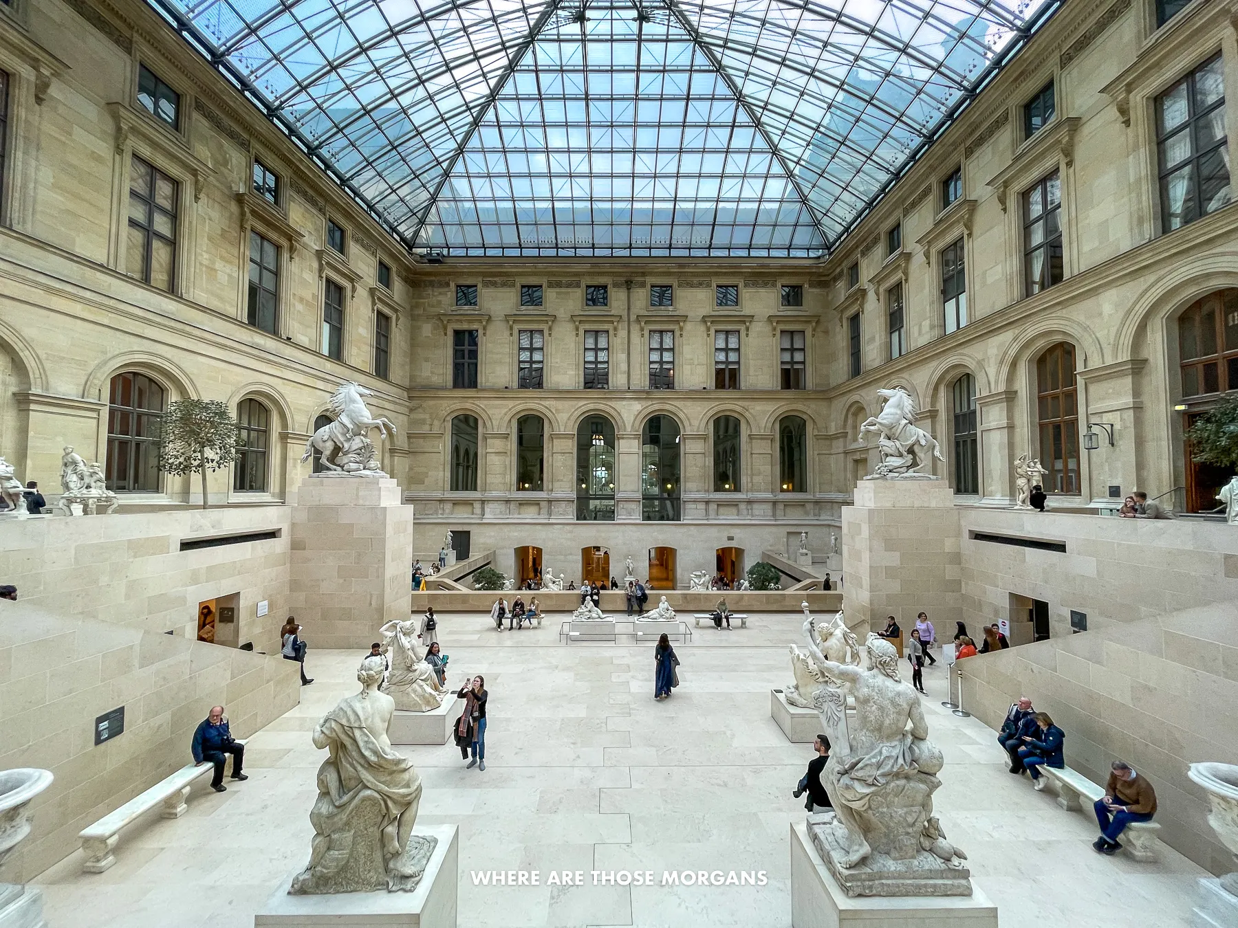 Photo of the cour marly indoor sculpture area of the Louvre Museum with lots of bright light flooding in through a glass roof