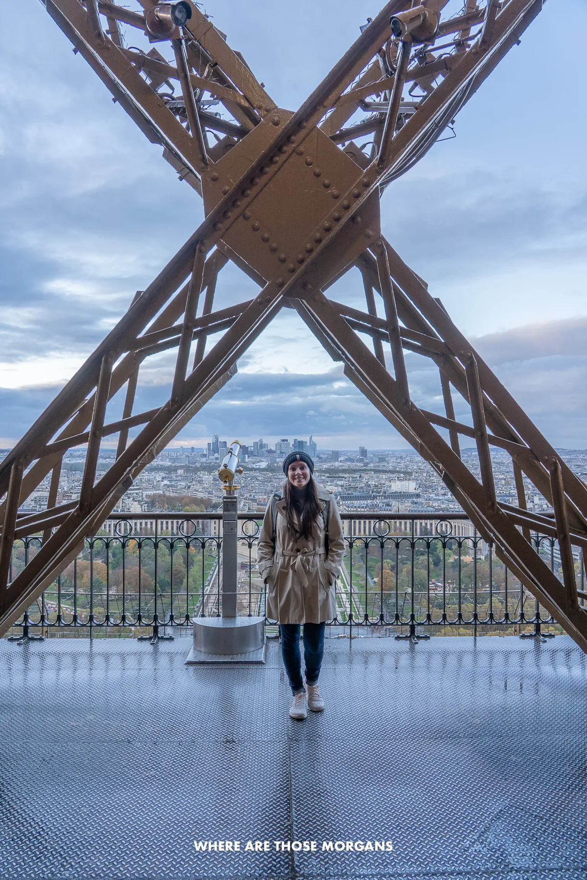 Kristen from Where Are Those Morgans standing on an observation deck in Paris at sunset with a big X-shaped iron structure behind