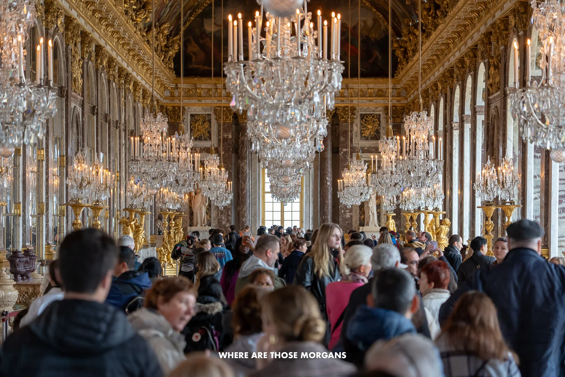 Massive crowds of people crammed into the Hall of Mirrors in the Palace of Versailles near Paris with tourists shoulder to shoulder through the entire room