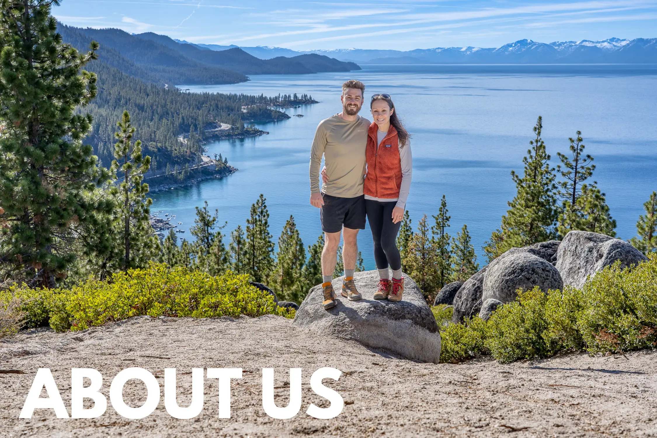 Photo of Mark and Kristen Morgan from Where Are Those Morgans stood together on a rocky hiking trail summit with evergreen trees and a huge lake behind on a sunny but cool day in Lake Tahoe, along with the words About Us overlaid