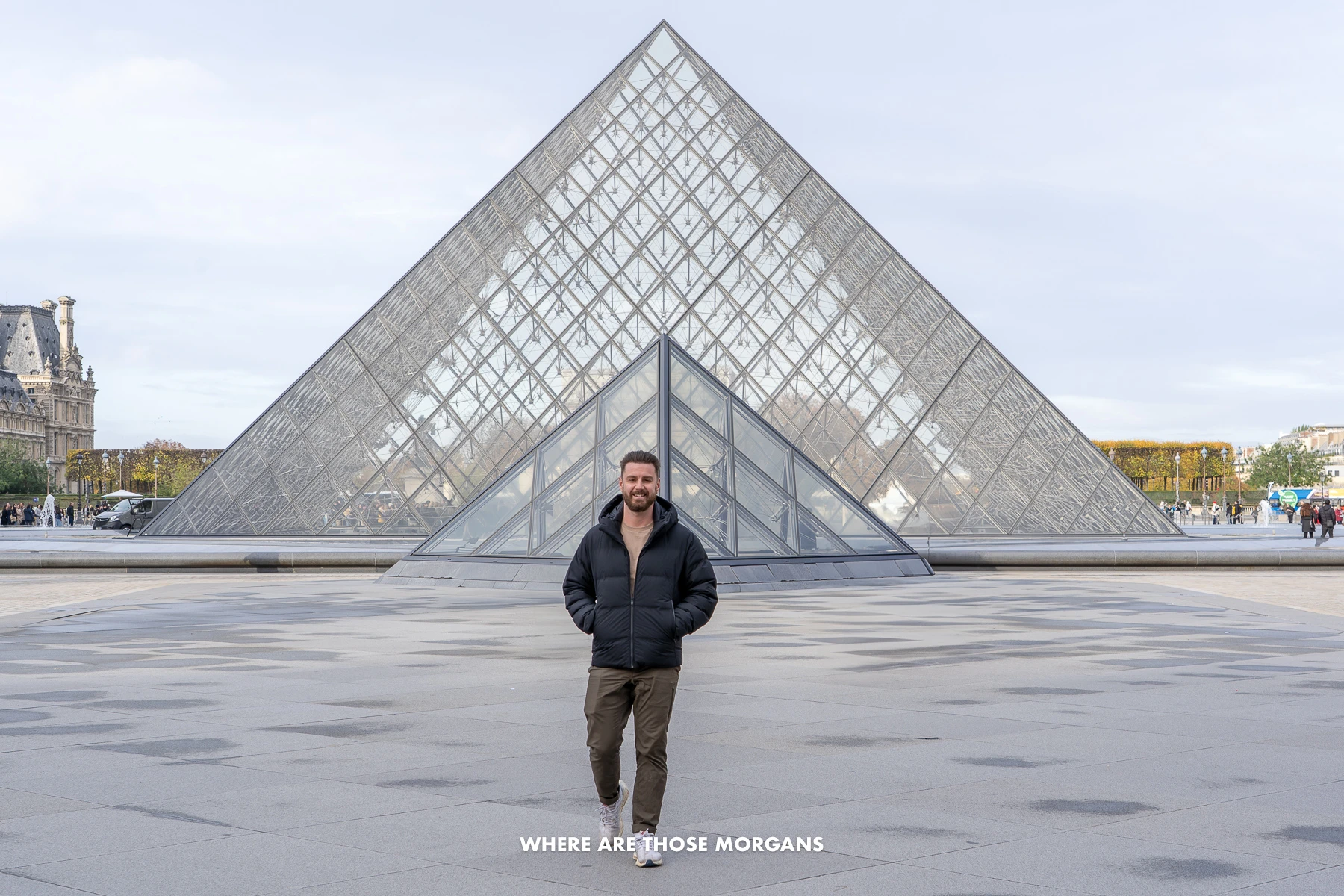 Photo of Mark from Where Are Those Morgans walking in front of the glass pyramid at the Louvre Museum in Paris on a cold day with no crowds