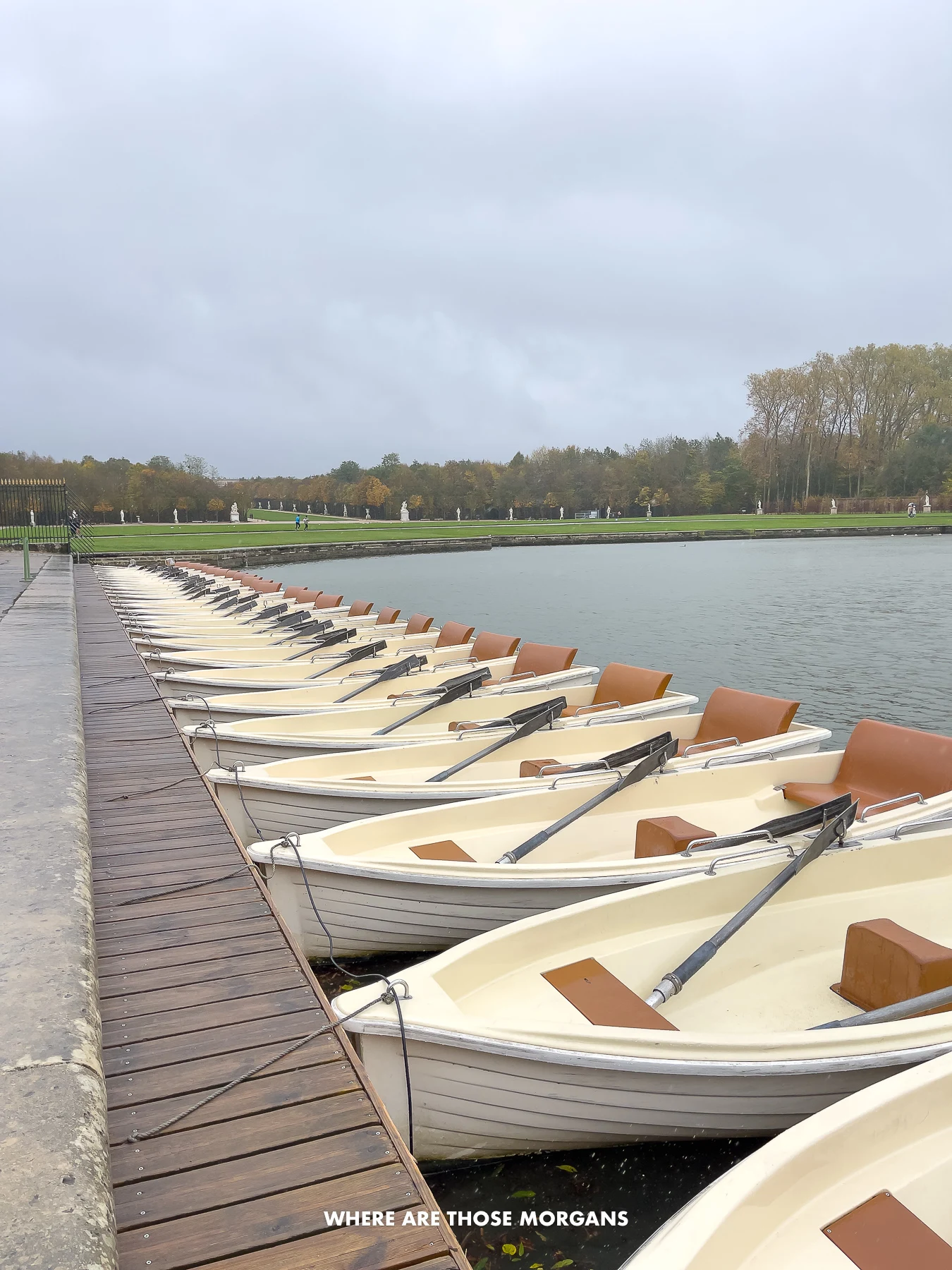 Long line of rowing boats tied on a dock with heavy clouds in the sky
