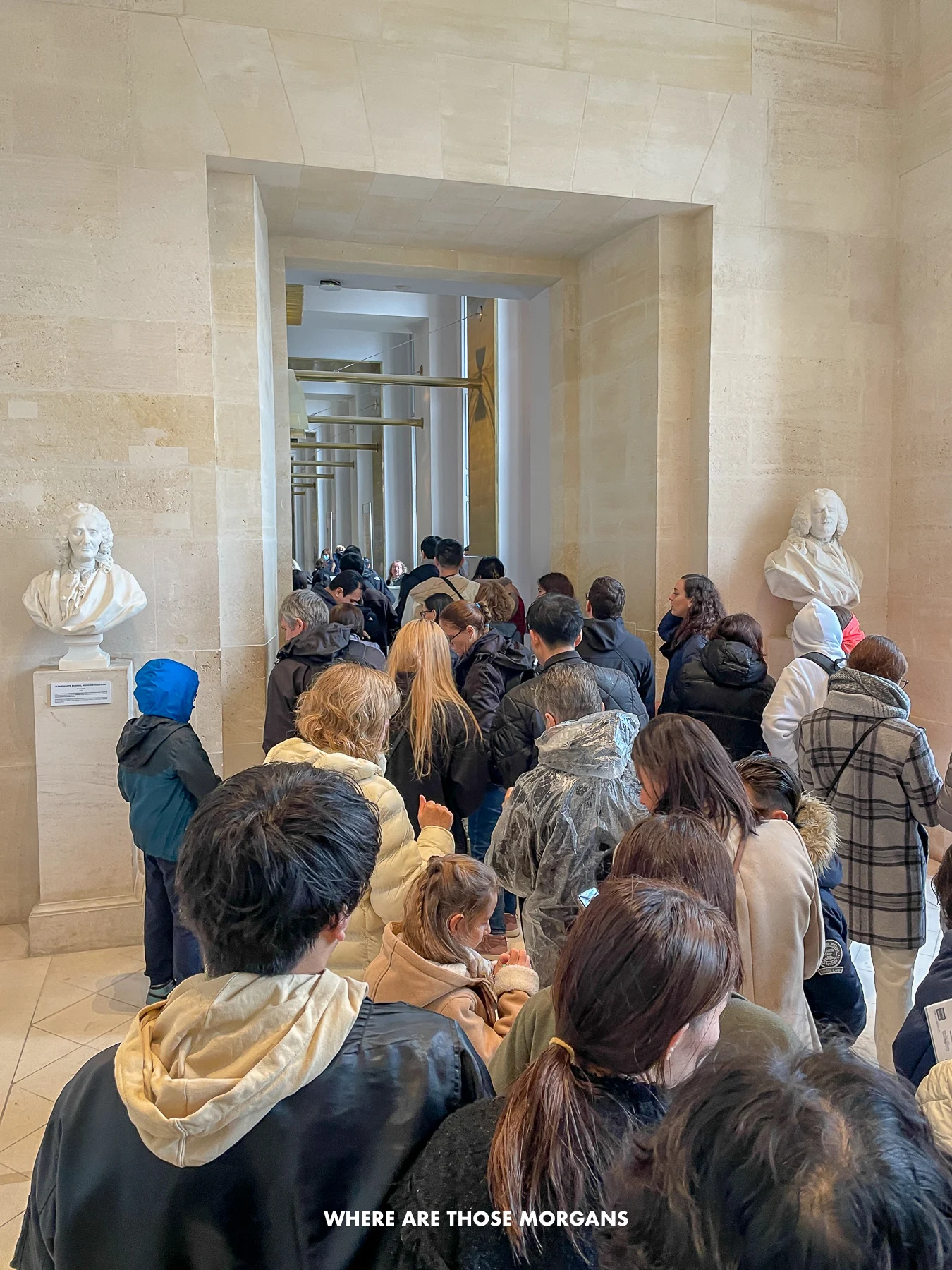 Long line of people inside a marble room waiting to pass through a security check point inside a museum in Paris