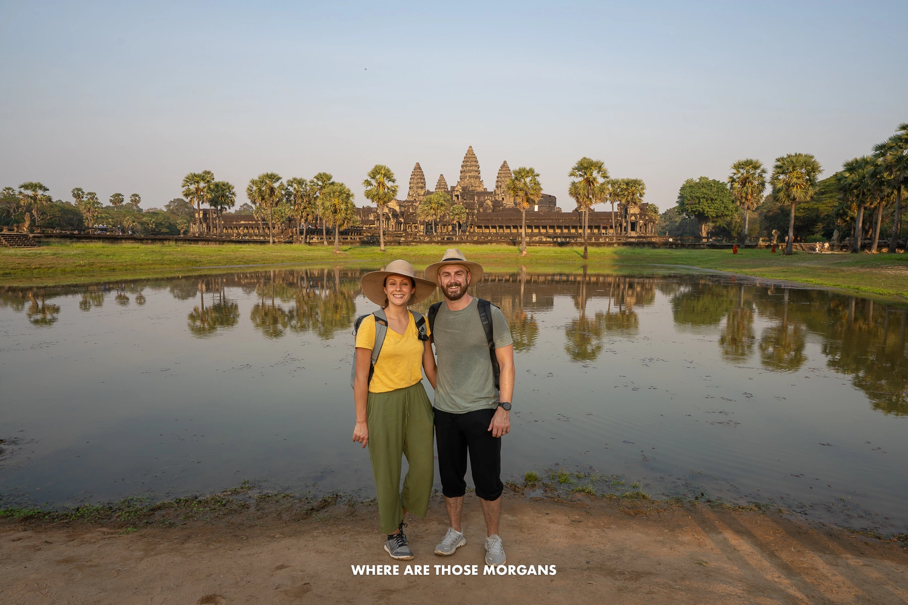 Photo of Mark and Kristen Morgan standing together in front of a small pond at Angkor Wat for sunrise in Cambodia