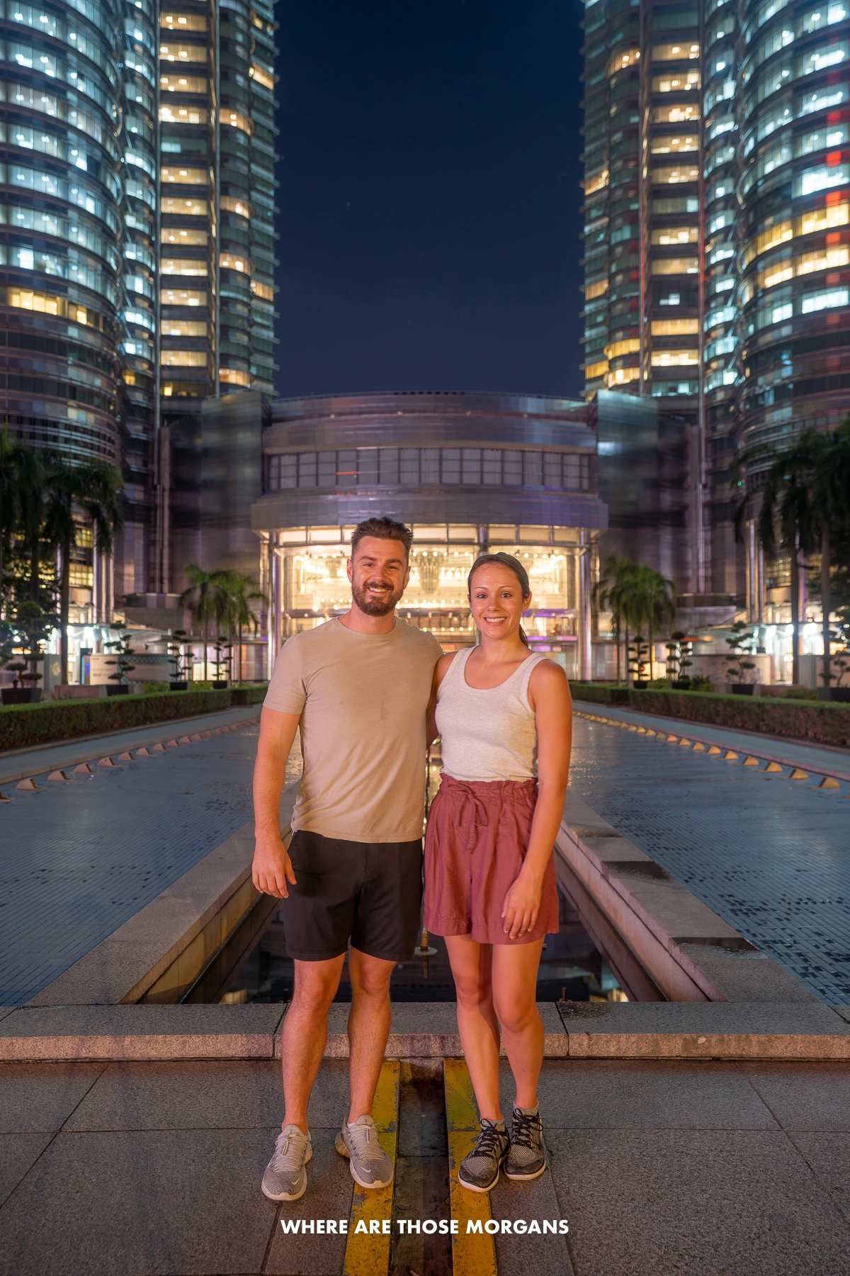 Photo of Mark and Kristen Morgan standing together in front of the Petronas Towers in Kuala Lumpur at night