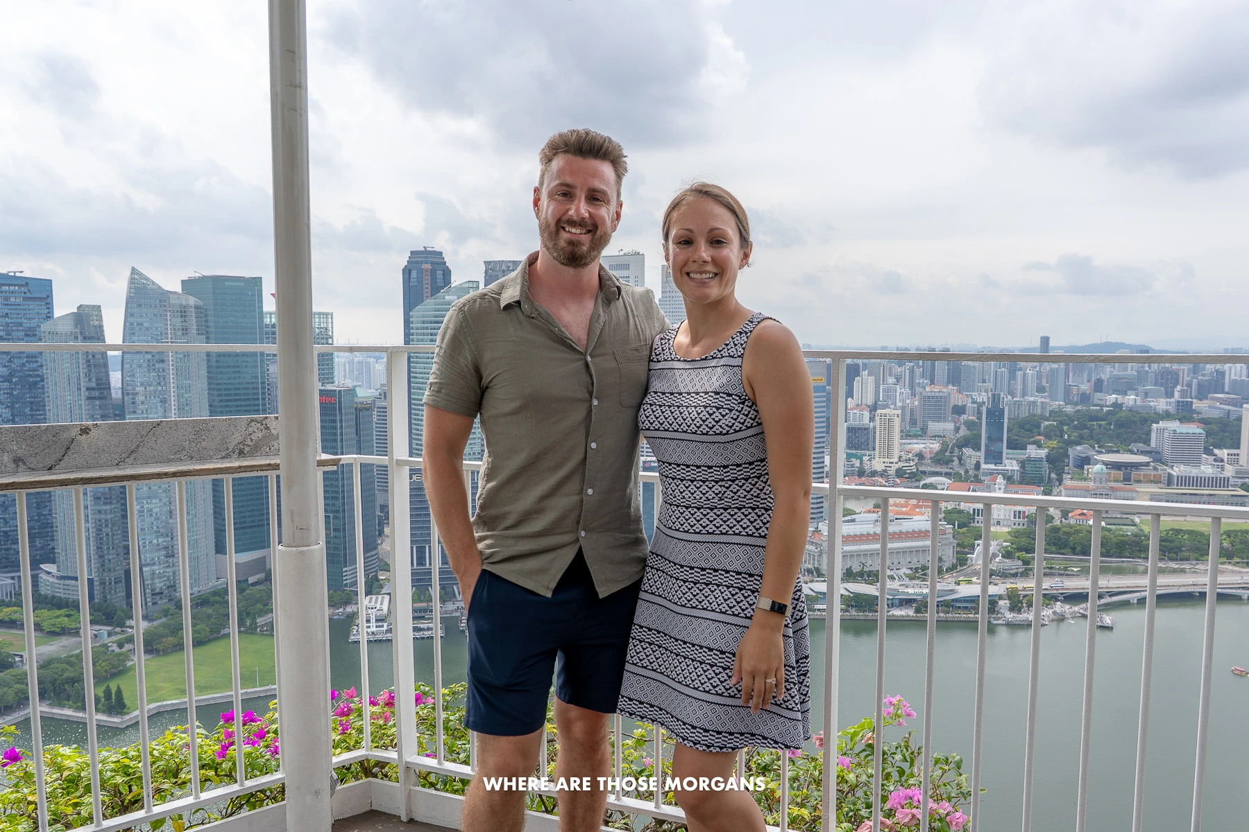 Photo of a couple standing together on an elevated balcony overlooking the city of Singapore on a cloudy day