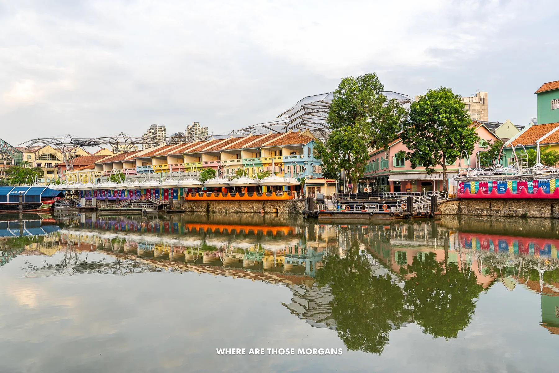 A river with colorful low rise buildings and trees on the far bank