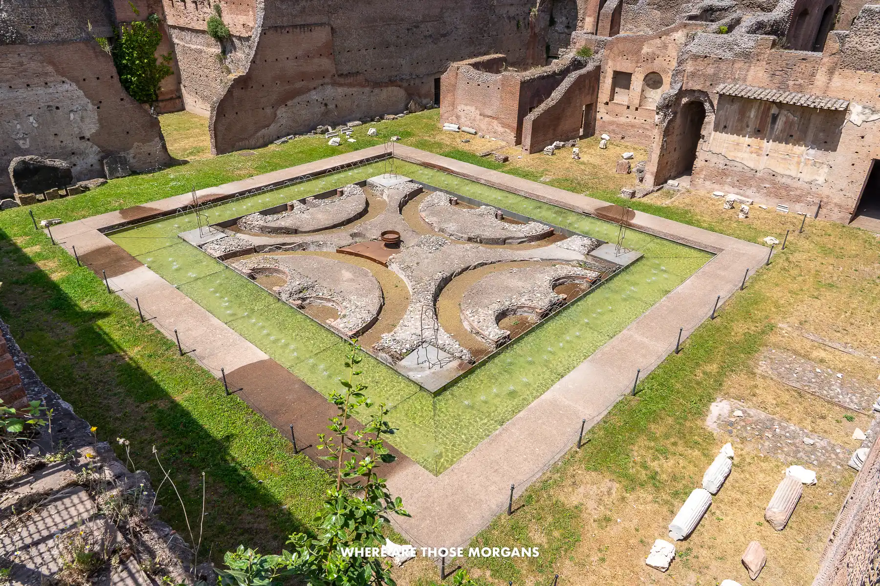 Remains of Domus Augustana in the Roman Forum with grass growing in a square shape around stones and rocks