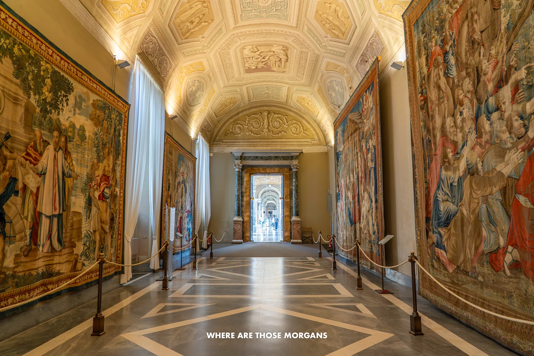 Huge tapestries hanging on the sides of a giant hallway in Rome