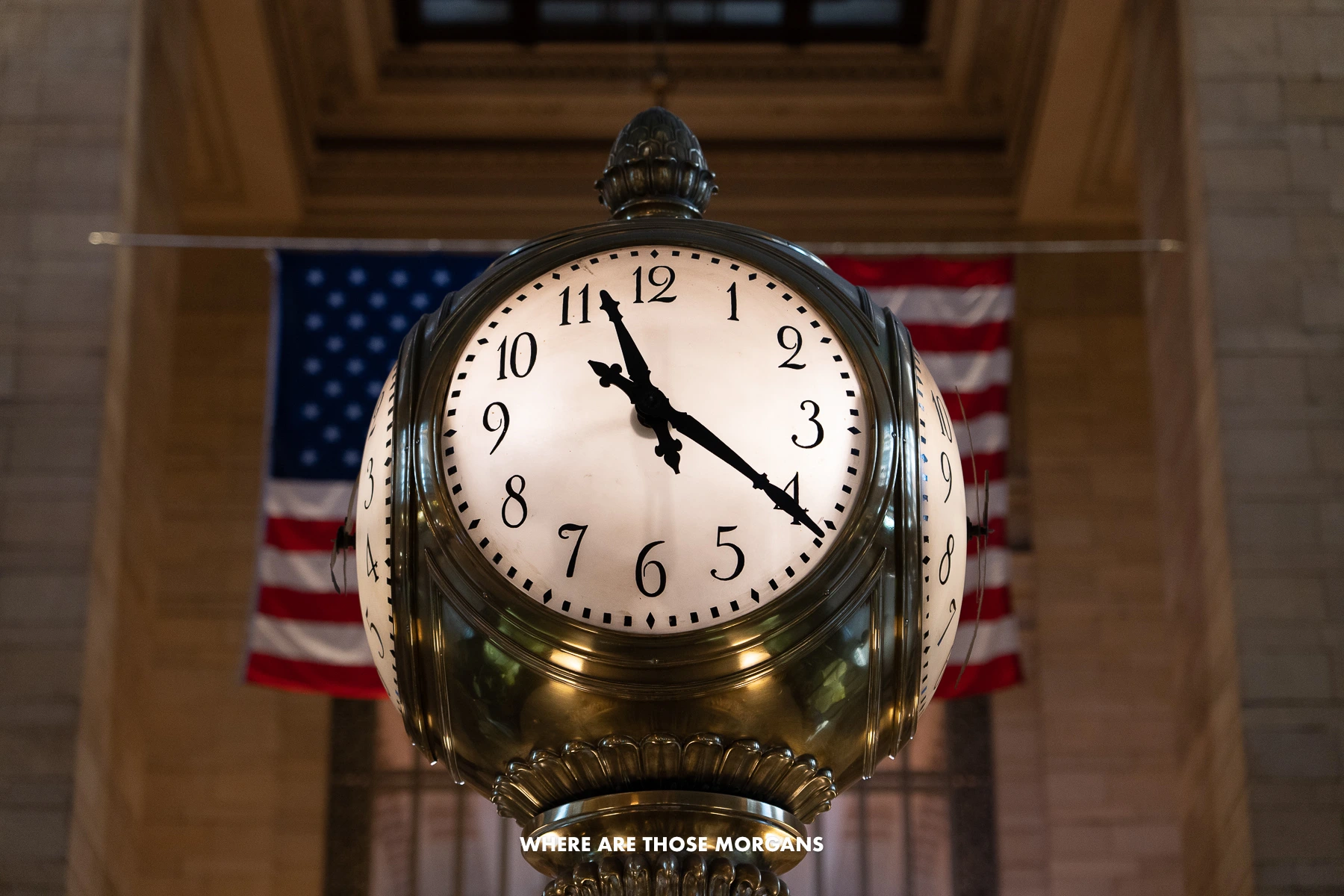 Close up of the 4 sided clock in Grand Central Terminal with an American flag behind