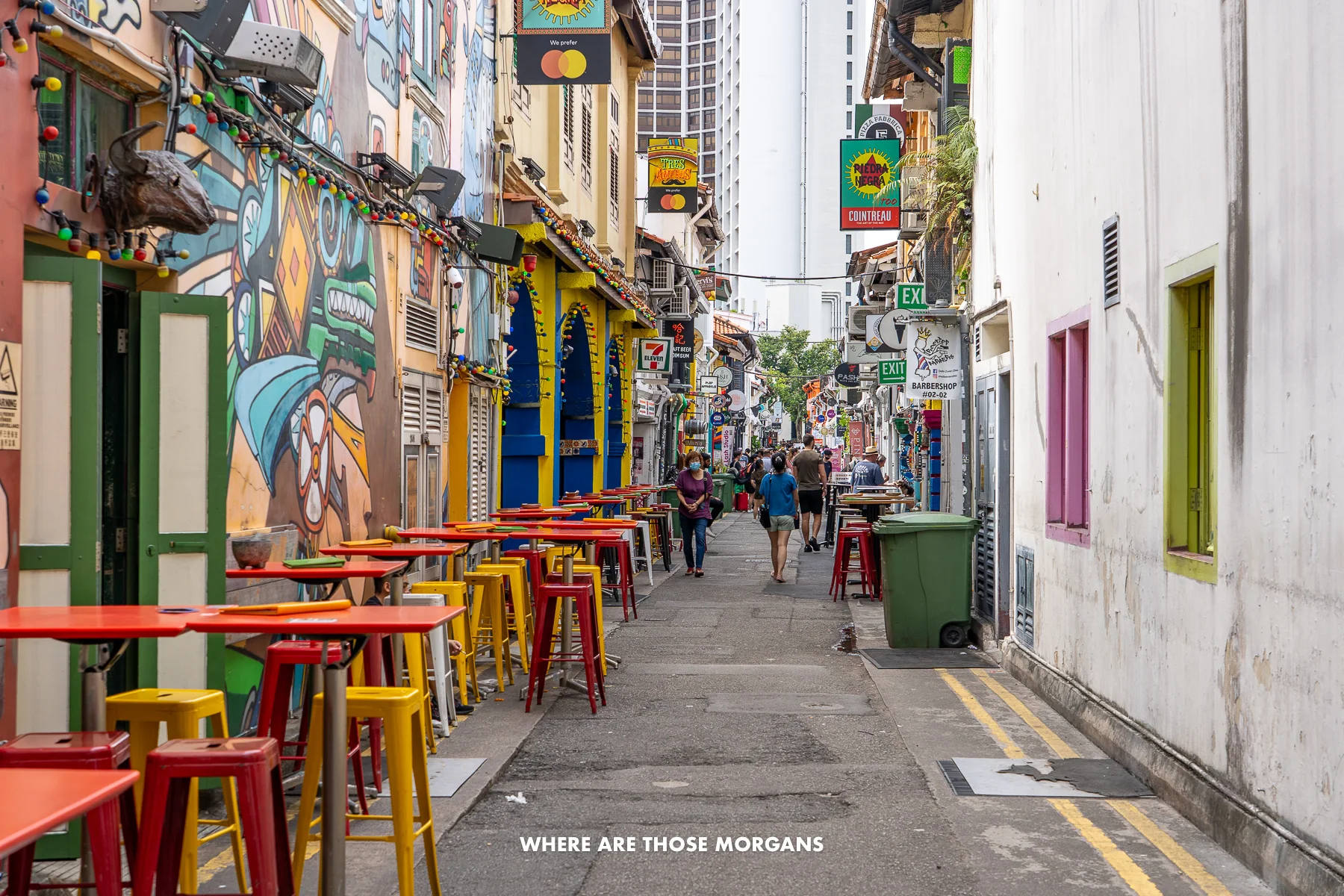 Narrow street with colorful buildings, tables and chairs outside restaurants