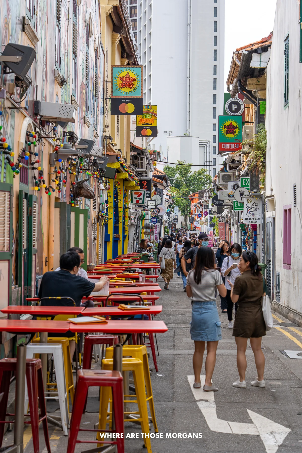 A narrow street in Kampong Glam Singapore called Haji Lane with colorful buildings and eateries with tourists walking the street