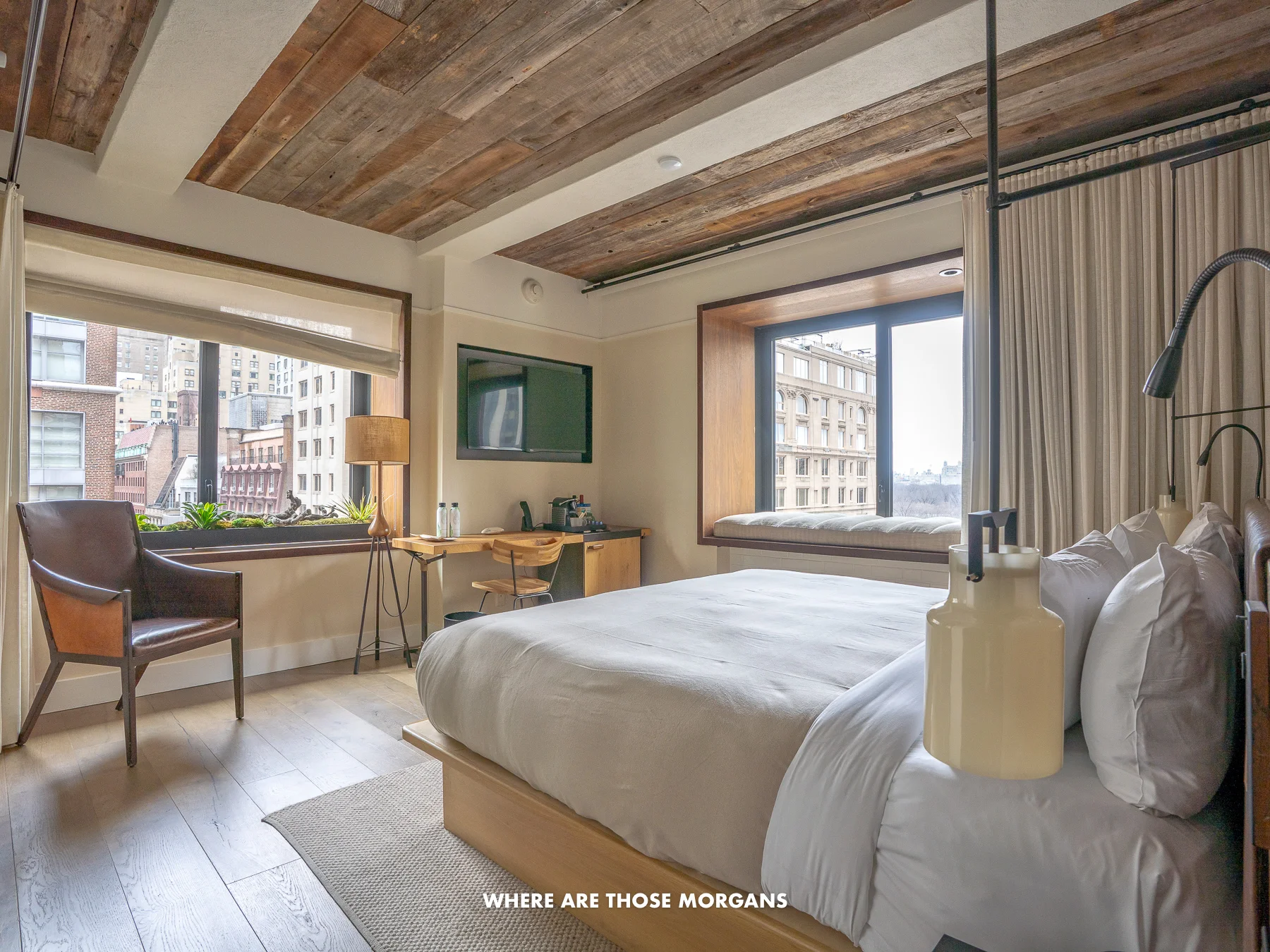 Inside a guest room at 1 Hotel Central Park in NYC with wooden finishes and a large bed with white sheets