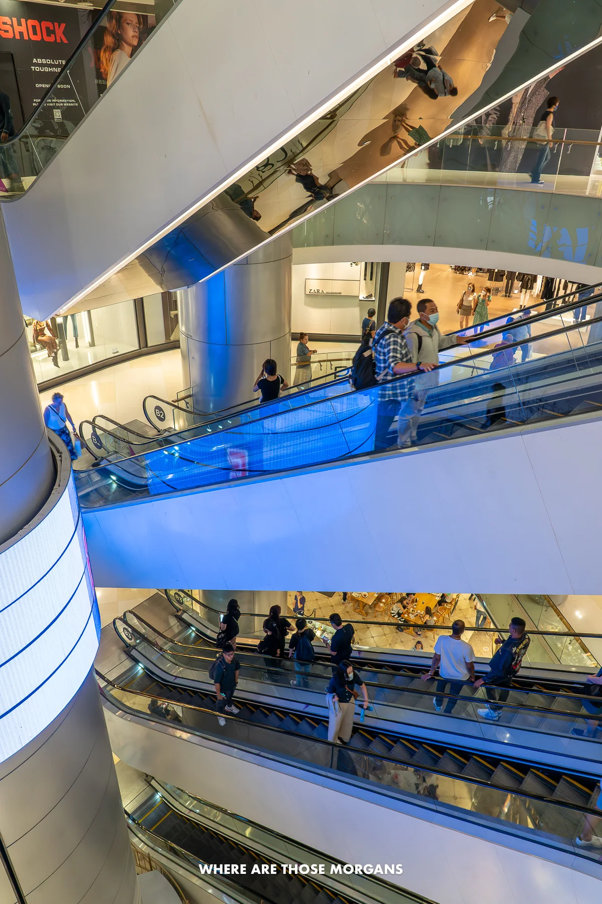 Looking down through an underground shopping mall at escalators and shoppers