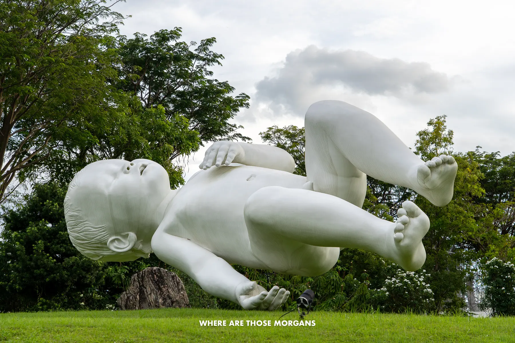 A giant floating white baby sculpture called Planet in Gardens by the Bay in Singapore on a cloudy day