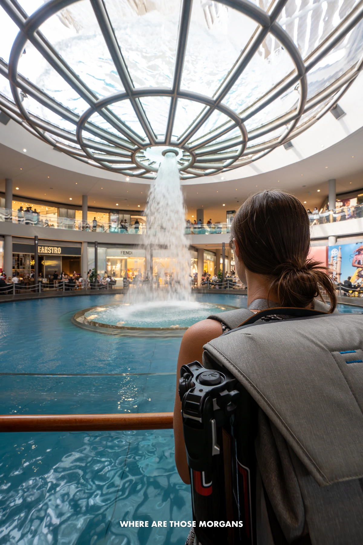 Kristen from Where Are Those Morgans looking at water falling through a hole into a canal inside a shopping mall in southeast Asia