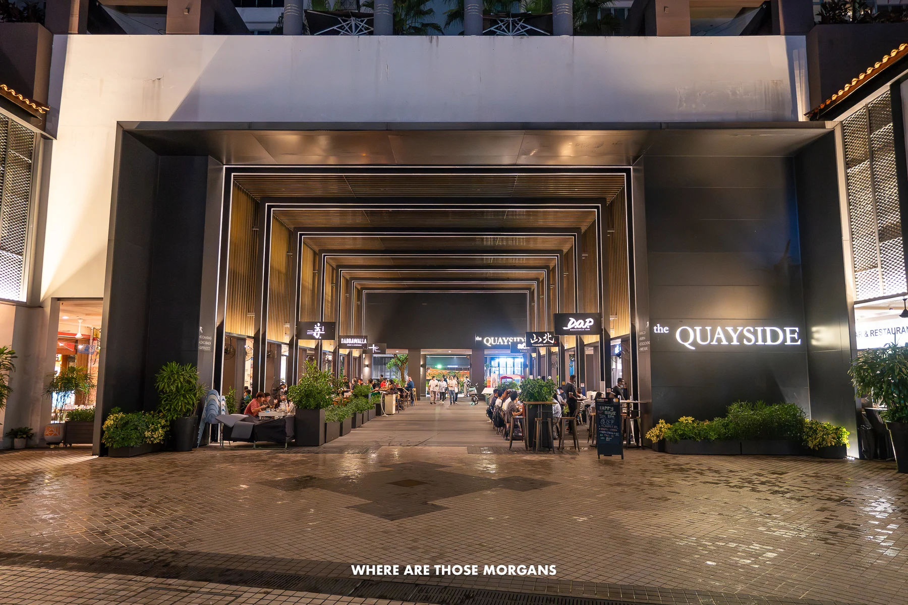 Large square shaped arch at the bottom of a skyscraper lit up at night in Asia