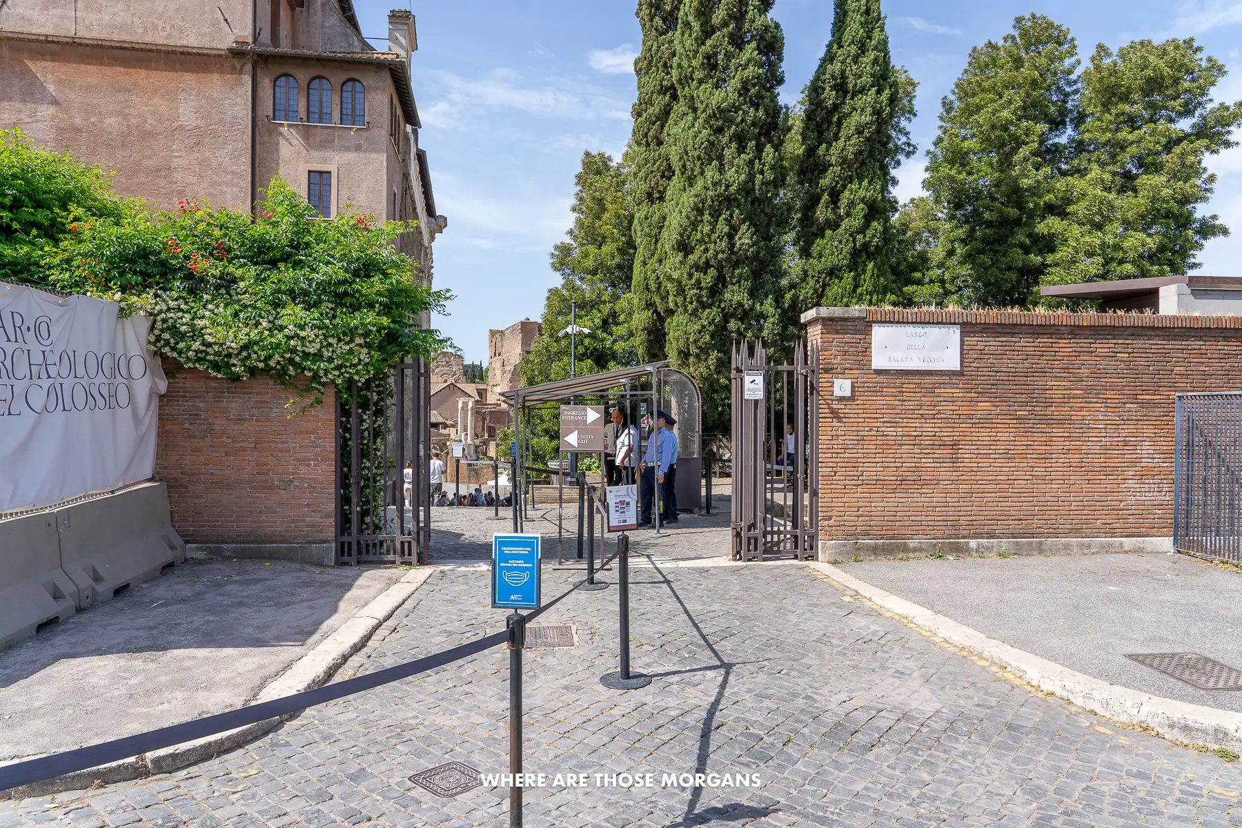 Hidden entrance to an archaeological park in Rome with black metal gates built into a brick wall