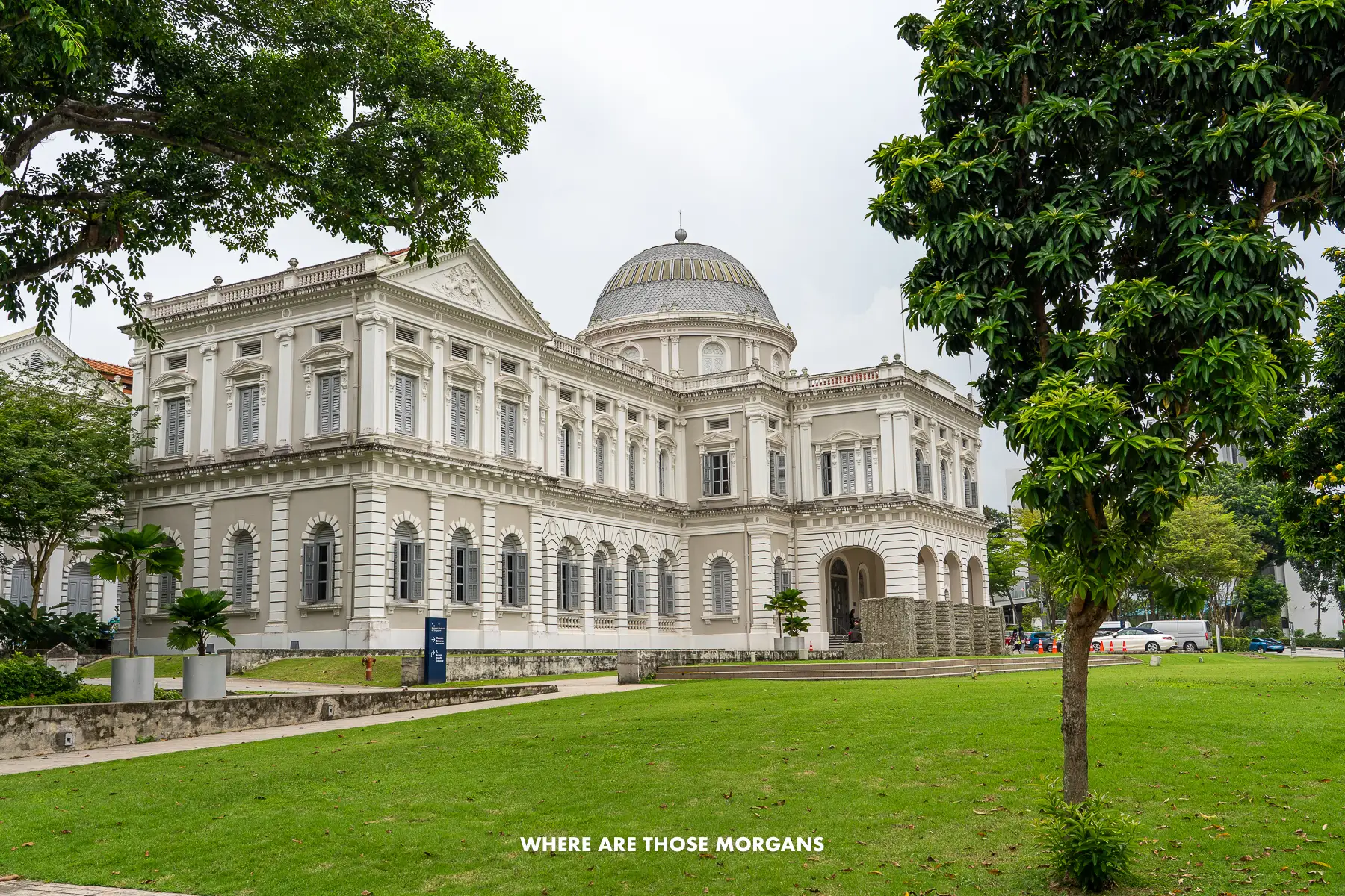Photo of the Singapore National Museum from outside and to the side with trees in the foreground
