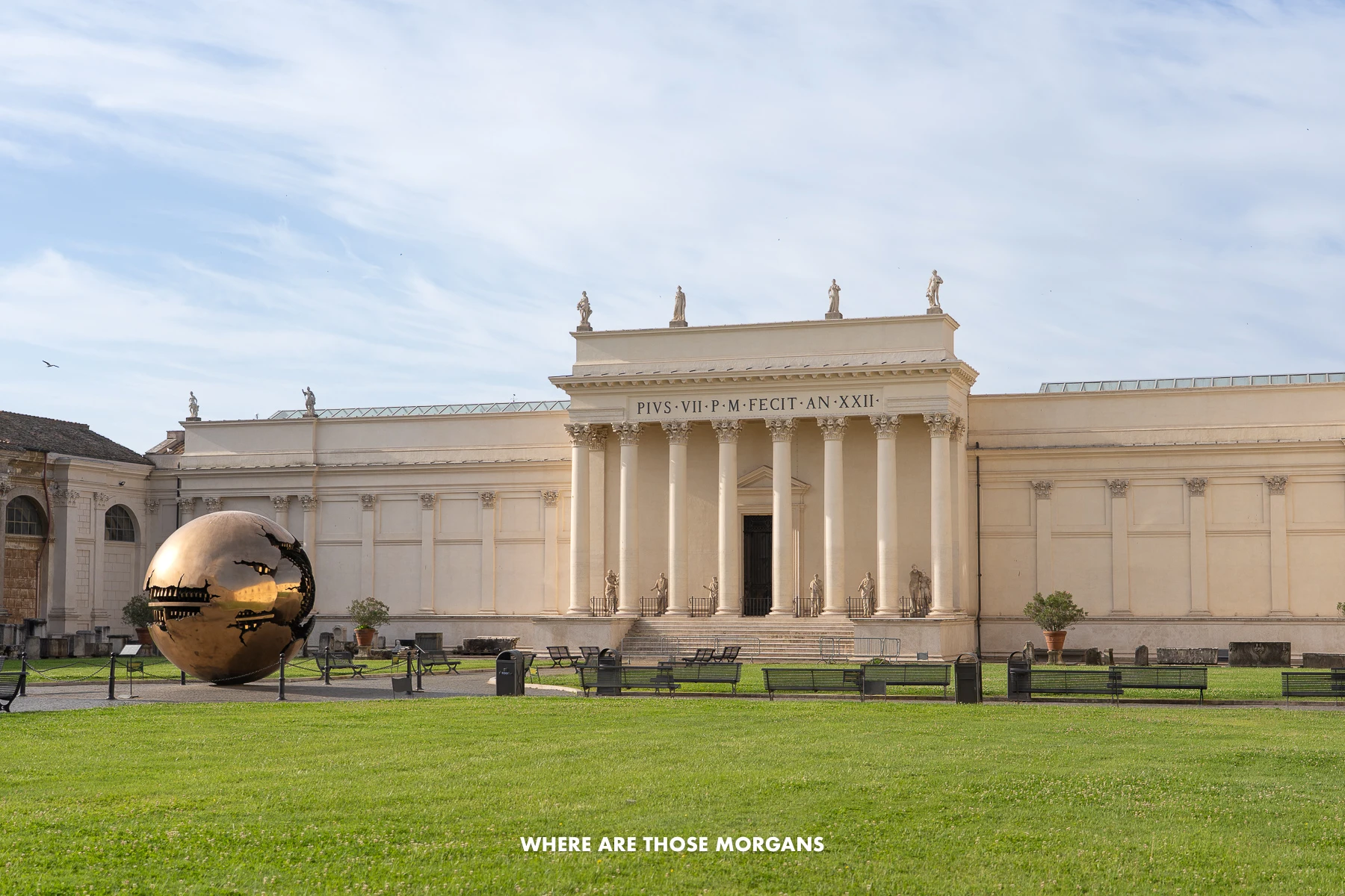 Photo of Pinecone Courtyard with green grass leading to a white building with columns and a huge modern sculpture called Sphere within Sphere