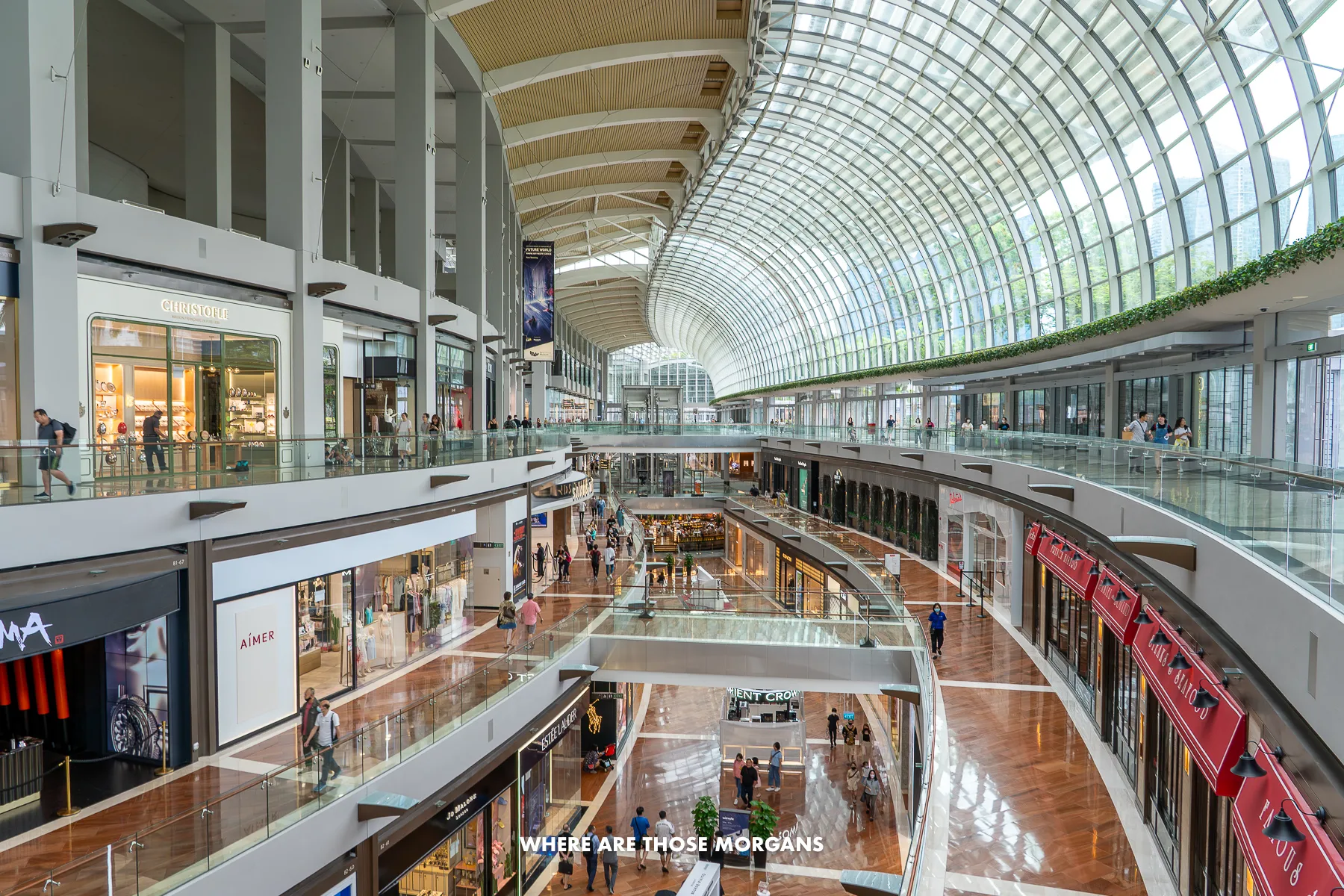 Inside The Shoppes at Marina Bay Sands with three floors of tourists shopping under a massive glass window