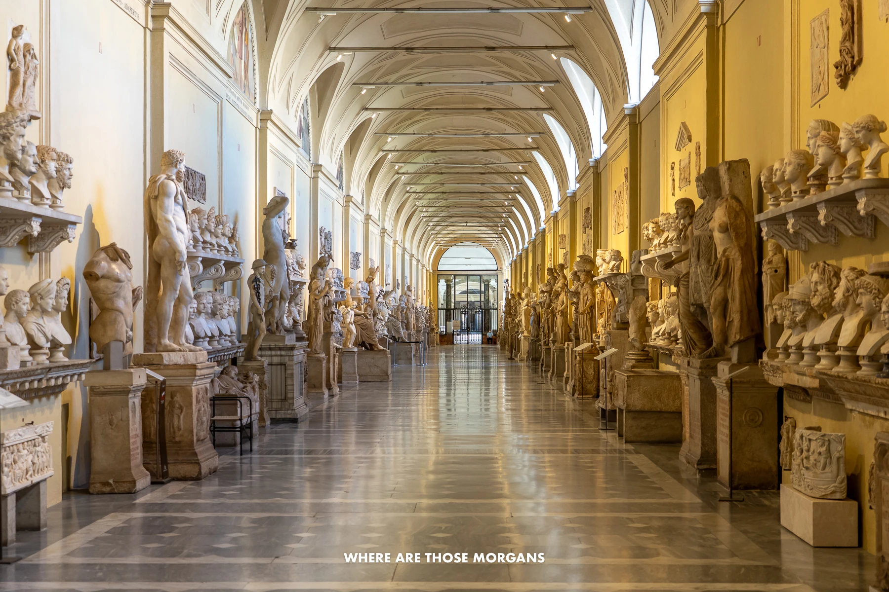 A long hall filled with sculptures and no people inside the Vatican Museum