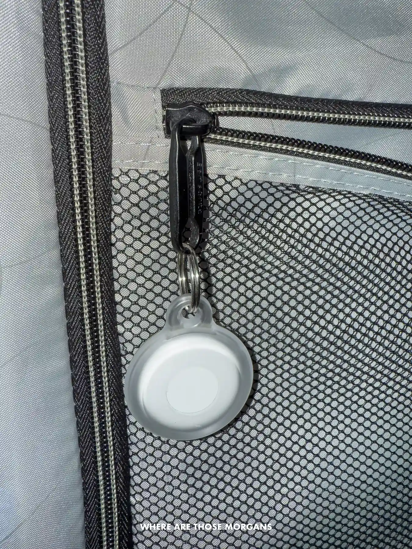 Photo of an Apple AirTag clipped onto a zipper inside a suitcase