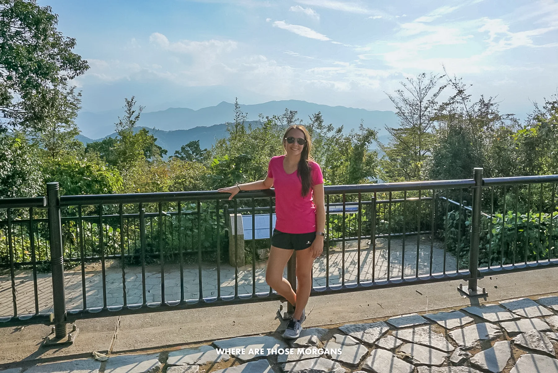 Kristen from Where Are Those Morgans standing at a viewpoint at the top of a mountain with views over distant mountains