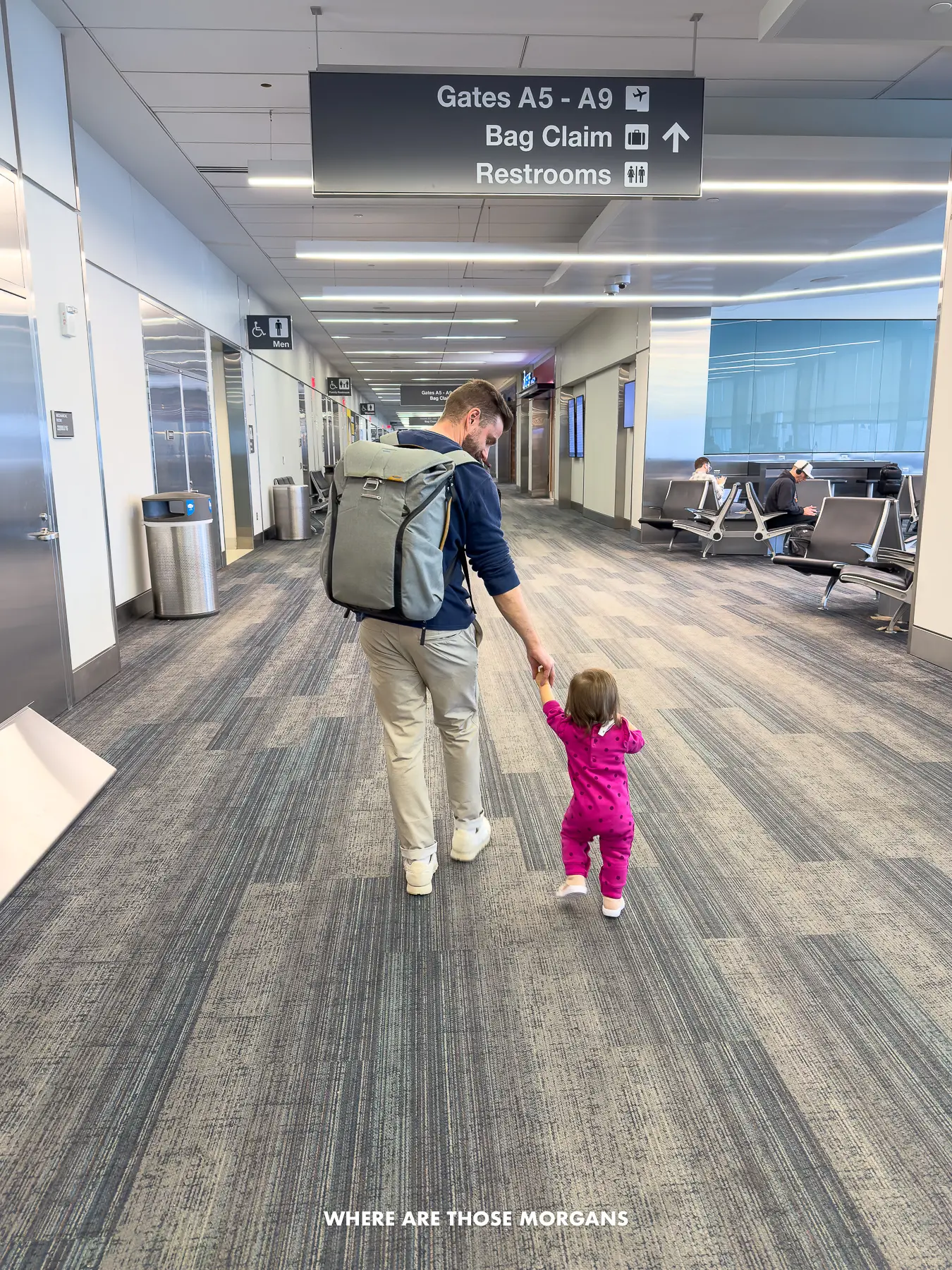 Mark Morgan wearing Bluffworks pants and Peak Design backpack walking through an airport with his daughter wearing a pink onesie