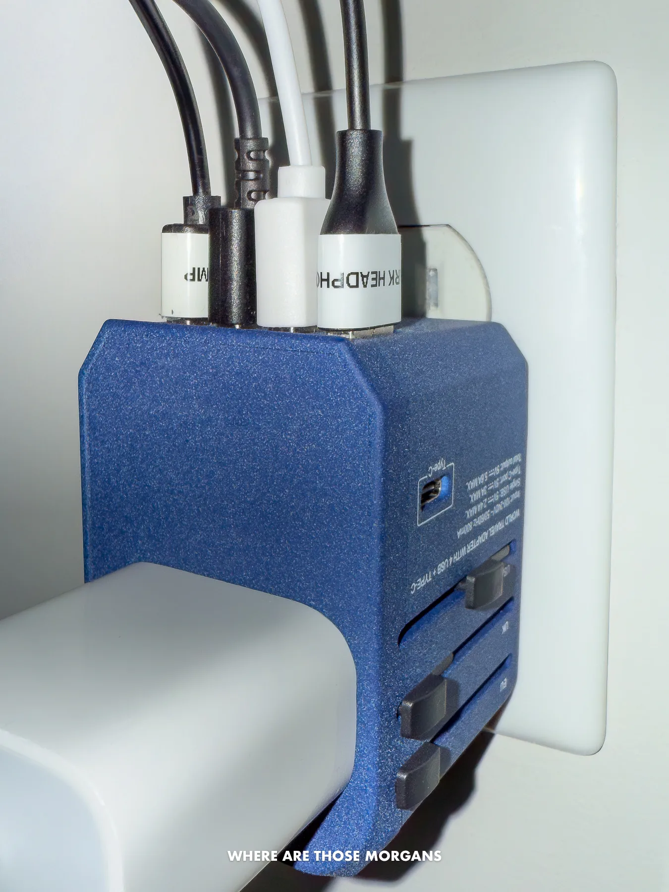 Close up photo of a plug adapter plugged into a socket with 4 usb cables plugged into the top